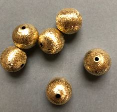 five gold colored beads on a gray surface