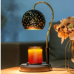 a table lamp next to a candle and some flowers