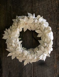 a white paper flower wreath on top of a wooden table