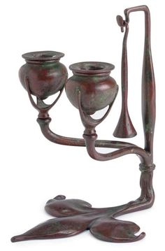 a metal candle holder with two candles on it's arms and one arm extended