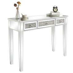 a white console table with two drawers and a clock on the top, against a white background