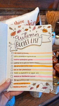 someone is holding up an autumn bucket list