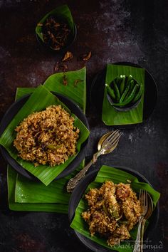 two plates filled with food on top of green leaf napkins next to silverware