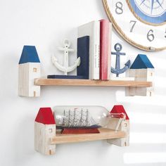 two wooden shelves with books, an anchor and a ship on them in front of a clock