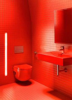 a red bathroom with a toilet, sink and mirror