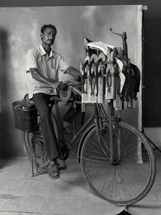 a man sitting on top of a bike next to a rack of shoes