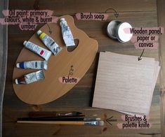 an artist's palette, paintbrushes, and other crafting supplies on a wooden table