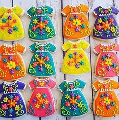 decorated cookies in the shape of children's dresses are displayed on a wooden table