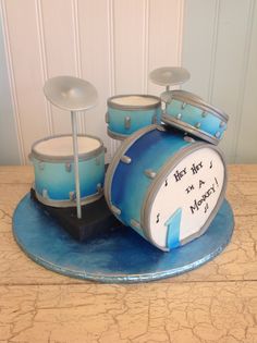 a cake shaped like a drum set on top of a blue plate with two sticks