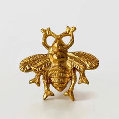 a golden bee brooch sitting on top of a white surface