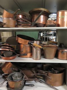 many pots and pans are stacked on shelves