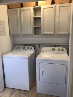 a washer and dryer in a small room with white cabinets on the walls