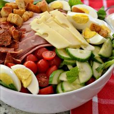 a salad with hard boiled eggs, tomatoes, cucumbers and other toppings