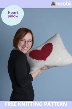 a woman holding a knitted heart pillow with the text free knitting pattern on it