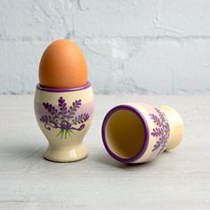 two egg cups with an egg in them on a white table next to a brick wall