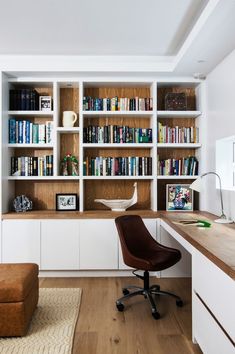 a chair sitting in front of a book shelf filled with books on top of a hard wood floor