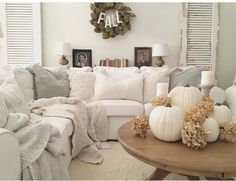 a living room filled with white furniture and lots of pillows on top of the couch