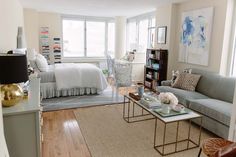 a living room filled with furniture next to a bed and a window covered in curtains