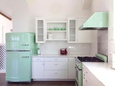 a green refrigerator freezer sitting inside of a kitchen next to a stove top oven