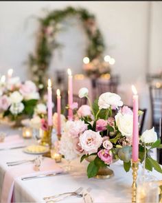 the table is set with pink and white flowers, candles, and napkins on it