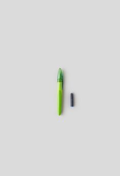 a green pen sitting on top of a white surface