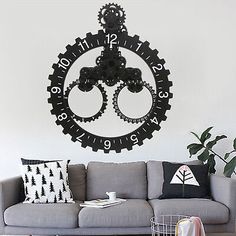 a living room filled with furniture and a clock wall decal on the wall above it