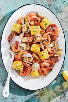 a white plate topped with shrimp, corn and clams