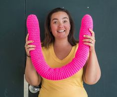 a woman holding up a pink object in front of her face and smiling at the camera