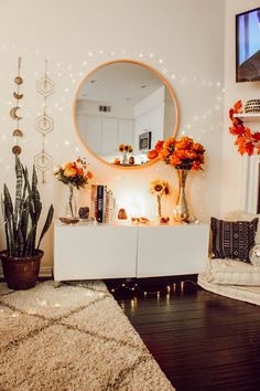 a living room with a large round mirror on the wall and flowers in vases