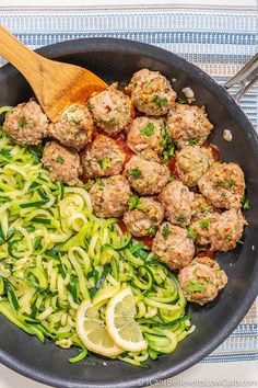 meatballs and zucchini noodles are in a skillet with a wooden spoon