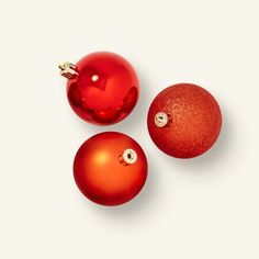 three red christmas ornaments on a white surface