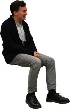 a man sitting on top of a chair with his legs crossed and looking off to the side