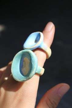 two small ceramic rings sitting on top of each other in someone's hand,