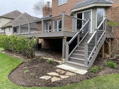 a house with stairs leading up to the front door and side yard area, surrounded by landscaping