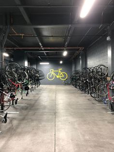 there are many bikes lined up in the garage with lights on and one bike is yellow