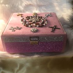 a pink box with beads and crosses on it sitting on a white furnishing