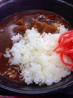 rice, meat and vegetables are in a black bowl