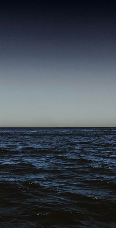 an airplane is flying over the ocean on a clear day with dark blue skies above