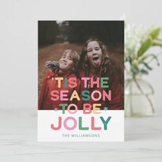 a card with the words tis the season to be jolly on it and two children