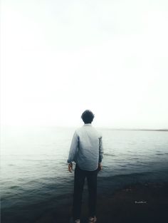 a man standing on the edge of a body of water looking out at the ocean