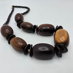 Vintage single strand wooden necklace. 24 inch statement piece. Large pieces of natural wood grouped with smaller wooden beads.  The wood in this piece represents the many colors of natural wood pieces. They range from a dark ebony color to a light brown. Each piece on the necklace is unique and makes a stunning piece of vintage jewelry when grouped together. The larger beads are 1 inches long X 3/4 of an inch wide. The smaller wood beads are 0.25 inches around. Vintage Wooden Beads Necklaces, Mahogany Wooden Beads Jewelry, Mahogany Colored Wooden Bead Jewelry, Natural Wood Necklaces With Wooden Beads, Artisan Natural Wood Necklaces, Earth Tone Jewelry, Ebony Color, Wooden Necklace, Wood Necklace