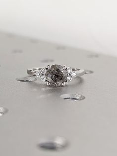 a diamond ring sitting on top of a silver surface with drops of water around it