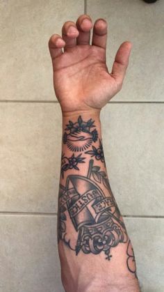 a person with a tattoo on their arm holding up his hand in the air while standing next to a tiled wall