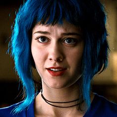 a close up of a person with blue hair wearing a choker necklace and looking at the camera