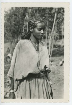 an old black and white photo of a young woman in native garb with birds around her neck