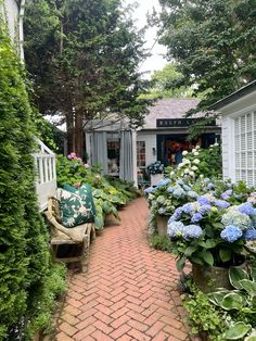 a brick path leads to a garden with blue and white hydrangeas on either side