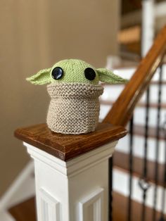 a knitted baby yoda hat sitting on top of a stair rail