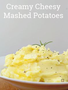 mashed potatoes in a white bowl on a wooden table with text overlay that reads creamy cheesy mashed potatoes