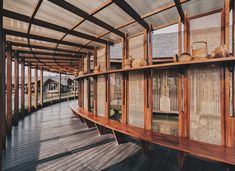 a wooden walkway lined with lots of windows next to a building covered in bamboo screens