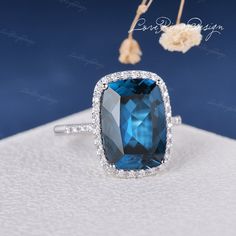 a ring with a large blue stone surrounded by white diamonds on top of a table